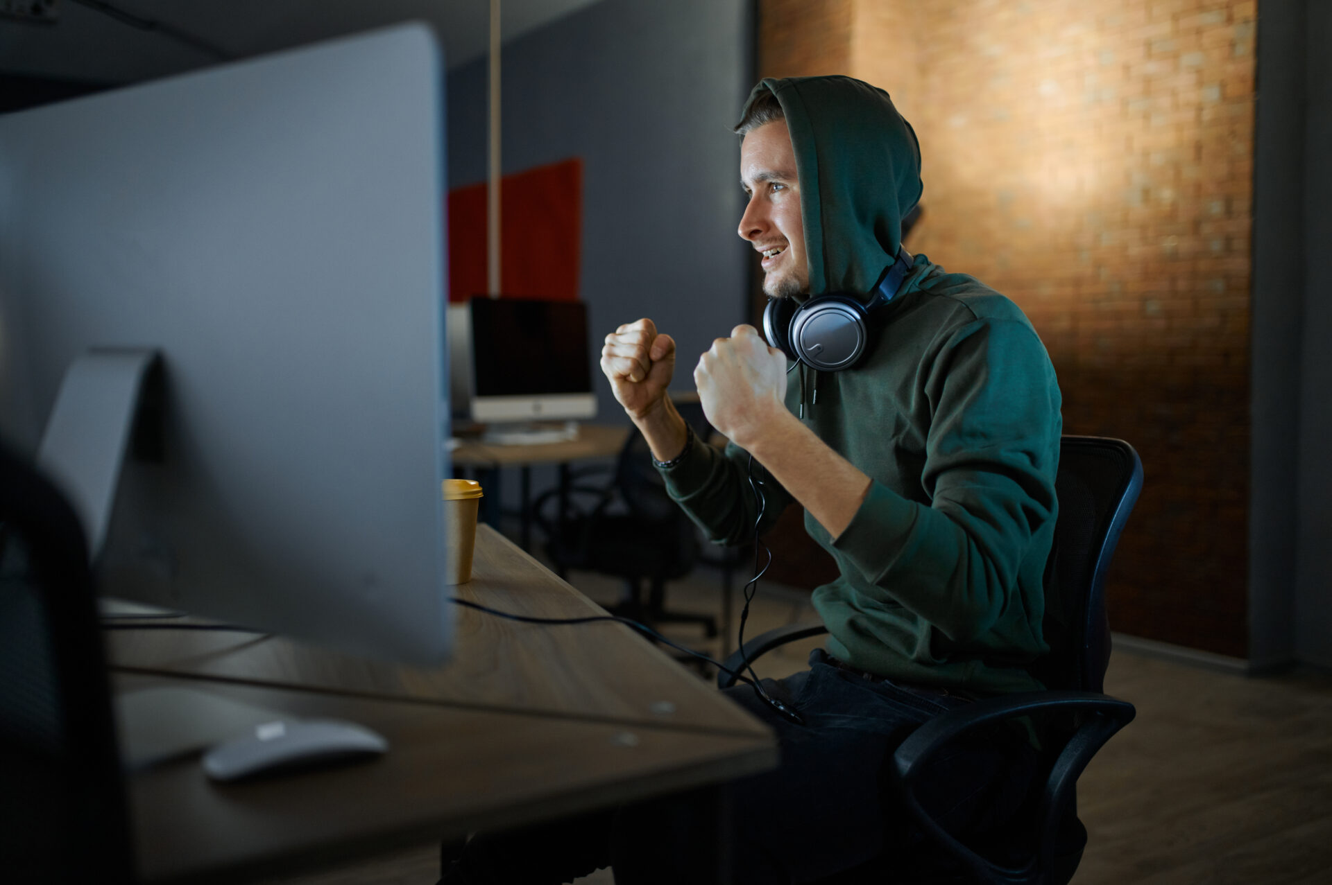 Happy male internet hacker in hood and headphones